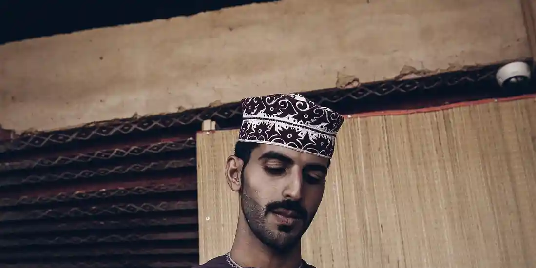 شاب يرتدي الكمة العمانية يركز في عمله